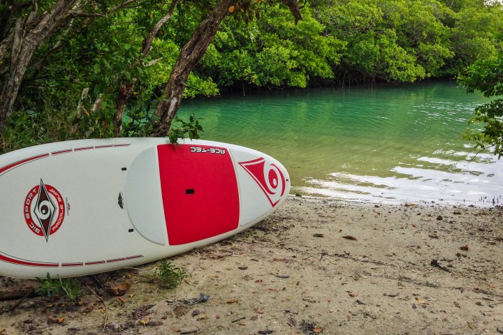 a beach with a surf board on a body of water